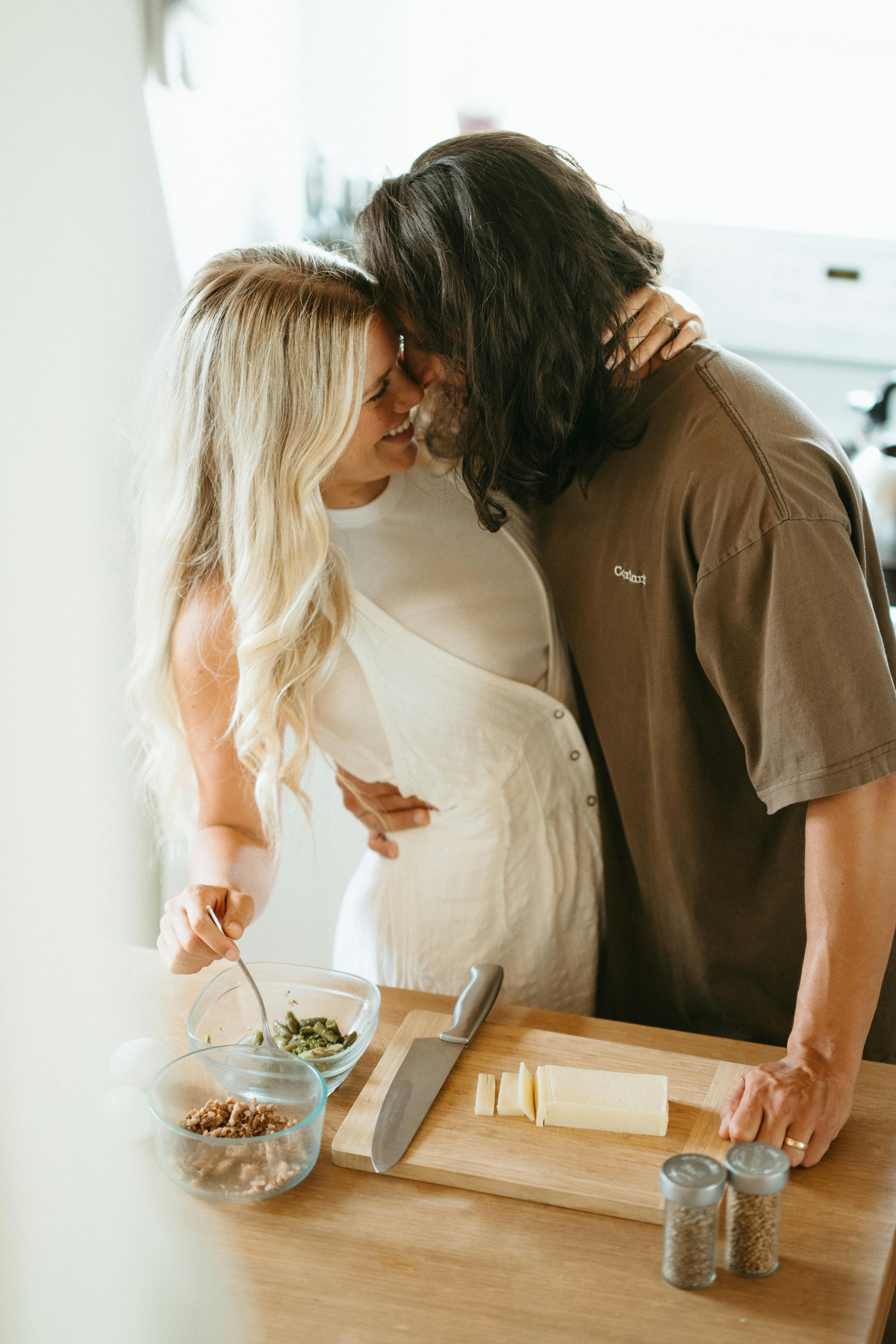 A couple lovingly preparing food together in the kitchen